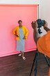 © VICTOR TORRES/Stocksy - Photographer capturing model in yellow blazer against pink backdrop