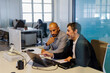© BONNINSTUDIO/Stocksy - Two businessmen discussing work on laptop in modern office