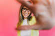 © VICTOR TORRES/Stocksy - Smiling woman staring through fingers against pink background