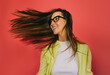 © VICTOR TORRES/Stocksy - Young woman flipping hair while smiling against a vibrant red backdrop