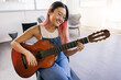 © VICTOR TORRES/Stocksy - Asian woman playing an acoustic guitar while smiling in a bright room