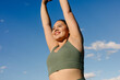 © Adrian Rodd/Stocksy - Medium shot of an empowered plus-size woman stretching outdoors