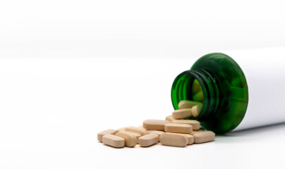 Wall Mural - Pills come out of a green medicine bottle. copy space selective focus isolated on white background