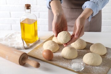 Wall Mural - Woman making dough ball at white wooden table, closeup