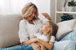 © SHOTPRIME STUDIO - Mother and daughter sharing a warm moment on the couch in a cozy living room, smiling at each other