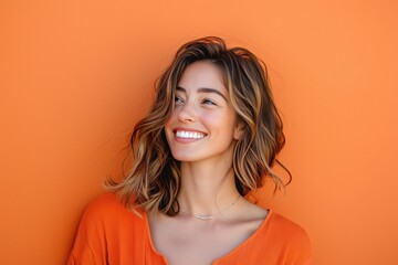 Portrait of a smiling woman with brown hair against an orange wall