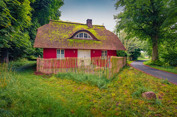 Wall Mural - Traditional rustic architecture in Ralswiek village with red wooden facade and straw roof, Germany, Europe. Marvelous summer scene of german countryside. Traveling concept background.