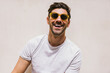 © VICTOR TORRES/Stocksy - Man wearing sunglasses with a bright smile and casual white t-shirt