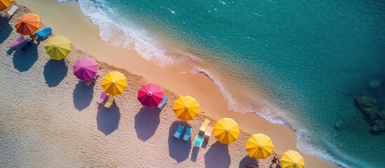 Sticker - Aerial View of Colorful Umbrellas on a Sandy Beach with Crystal Clear Ocean Water