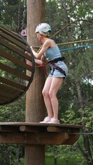 Wall Mural - A young woman in equipment and a helmet and belay undergoes a test in a rope park