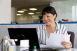 © Jovo Jovanovic/Stocksy - Smiling businesswoman working at desk in office