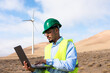 © Adrian Rodd/Stocksy - Engineer works with a laptop computer, outdoors, at a wind farm