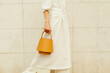 © Ulas&Merve/Stocksy - Stylish Woman Holding Yellow Handbag Against Tile Wall