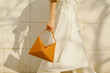 © Ulas&Merve/Stocksy - Elegant Woman Holding Geometric Handbag Against Neutral Backgrou