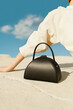 © Ulas&Merve/Stocksy - Stylish Black Handbag Outdoors Against Blue Sky