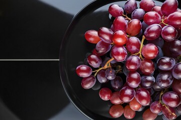 Wall Mural - A plate of grapes is shown in a black background