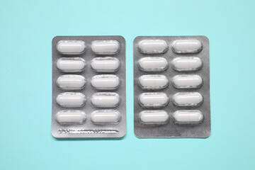 Wall Mural - Antibiotic pills in blisters on light blue background, flat lay