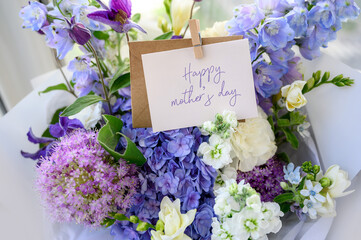 A bouquet of blue hydrangea, freesia close-up. Happy Mother's Day text. bouquet with delicate flowers. Greeting card, concept of sweet wish.