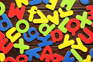 Poster - Magnetic letters on wooden background, flat lay. Learning alphabet