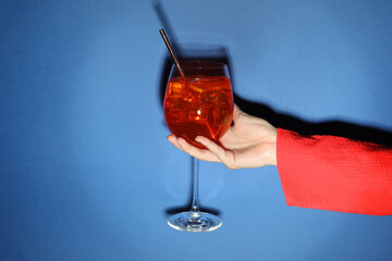 Wall Mural - Woman with glass of refreshing cocktail on blue background, closeup