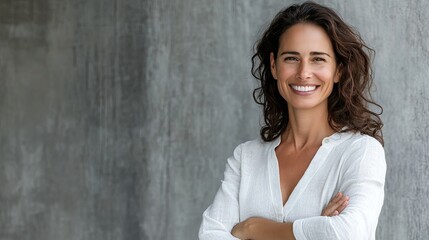 Wall Mural - A woman with long hair is smiling and wearing a white shirt. She is standing in front of a wall