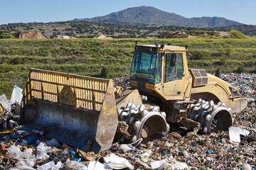 Wall Mural - Heavy machinery shredding garbage in an open air landfill. Pollution