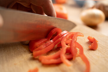 Close-up of man cutting red bell pepper on cutting board