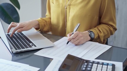 Professional business woman in yellow blouse is working on financial reports. Close-up of a woman's hands as she works on finance documents. Audit and taxes