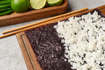 Canvas Print - Wooden board of nori with rice on light background, closeup