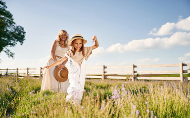 Wall Mural - Running, having fun. Beautiful mother with her daughter on the farm