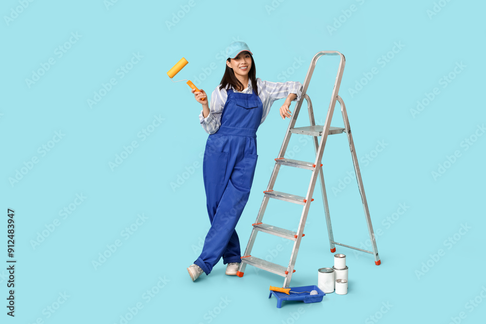 Female Asian painter with rollers, paint cans, tray and stepladder on blue background