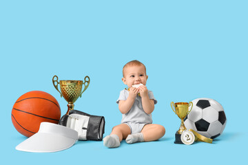 Wall Mural - Cute baby athlete with first place medal and sports equipment on blue background