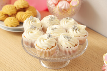 Wall Mural - Dessert stand with tasty white cupcakes for birthday party on wooden table