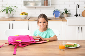 Canvas Print - Little girl packing backpack for school in kitchen