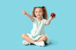 © Pixel-Shot - Cute little girl with red apple making heart gesture on blue background