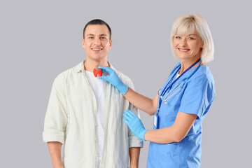 Wall Mural - Female endocrinologist with thyroid gland model and man on light background