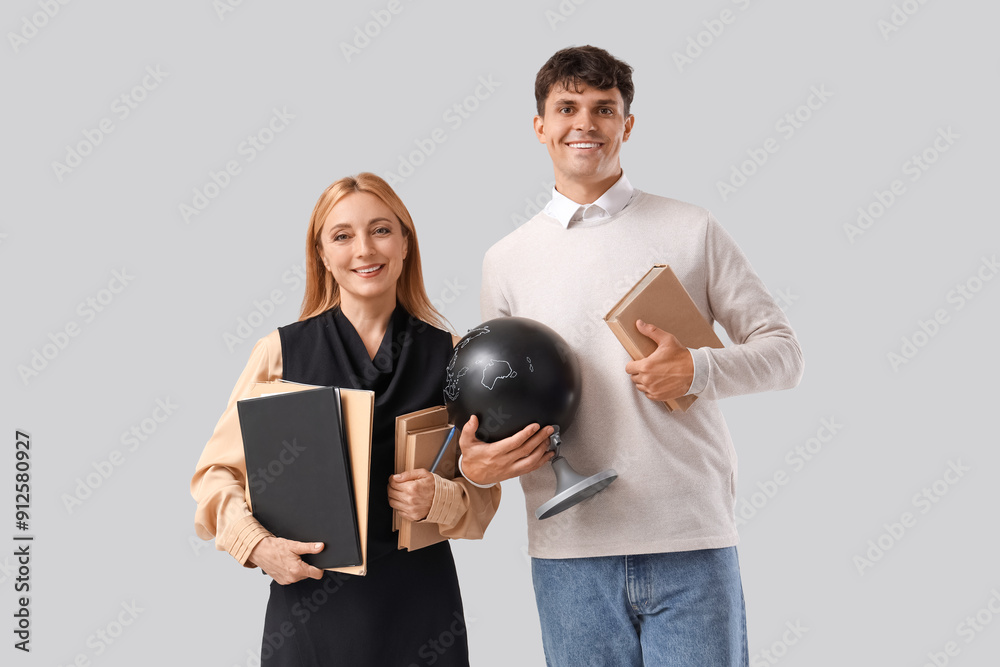 Teachers with globe and books on light background