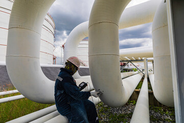 Wall Mural - Male worker inspection ultrasonic thickness at steel long pipes and pipe elbow in station oil factory during refinery valve of visual