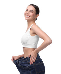 Poster - Diet and weight loss concept. Happy young woman in big jeans showing her slim body on white background