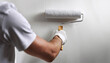 © Alberto Masnovo - Extreme closeup of the hand of a male house painter while using a paint roller on a white wall in a domestic room. home improvement and diy project concept. Generative Ai.