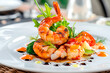 © Creative mind - Premium seafood cuisine. Closeup on grilled shrimp and fresh vegetable garnish plating with decorative sauce drizzle on white dish.