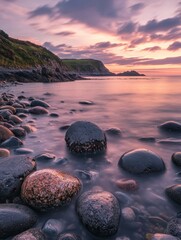 Wall Mural - Serene Sunset over Coastal Pebbles - A tranquil seascape with smooth, wet pebbles on the shore, bathed in the soft light of a sunset. The horizon is a gradient of purple and pink, and the water is cal