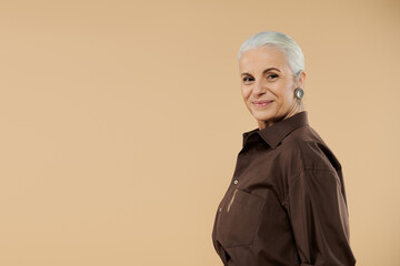 Wall Mural - A mature woman smiles warmly while posing on pastel backdrop.