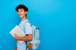 © InsideCreativeHouse - Attractive smiling boy guy high school male pupil student teenager in casual clothing with backpack holding using laptop, going to school with computer copy space isolated on blue background