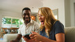 © Monkey Business - Young Couple or Friends Enjoying Handheld Gaming Together in a Bright Living Room