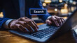 © mimi - A businessman conducts an online search on his laptop, a clear depiction of digital connectivity and information access in the modern corporate world.