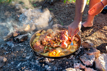 Hands cooking on a campfire while camping in the wild