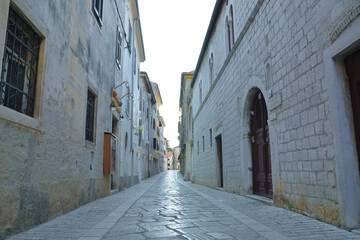 A narrow cobblestone street lies nestled between two historic stone buildings