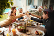 © Chanelle2000/peopleimages.com - Family, happy and cheers for Christmas, celebration and lunch at house with food, drinks and glass in backyard. Mom, dad and children for holiday, bonding and brunch with support, cheerful and fun