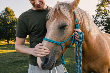man is embracing of therapy horse on sunny summer day. themes hippotherapy, care and friendship betw